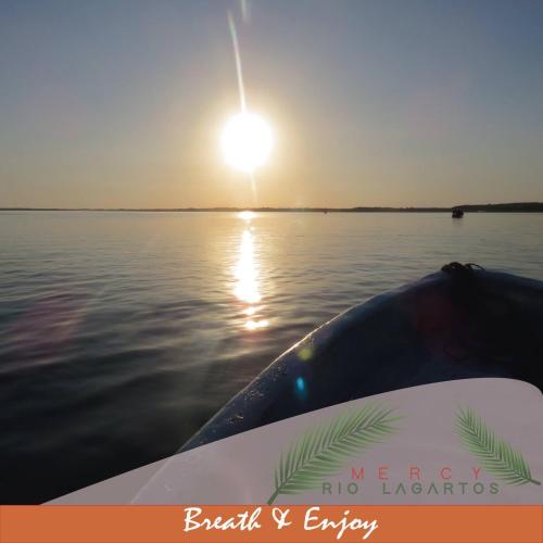 a boat on a body of water with the sun at Hotel Posada Mercy in Río Lagartos