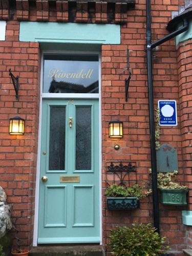 a brick building with a blue door next to a window at Rivendell Guest House in Keswick