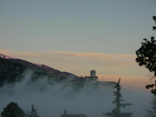 un edificio en la cima de una colina en la niebla en Sulla Strada di San Francesco, en Asís