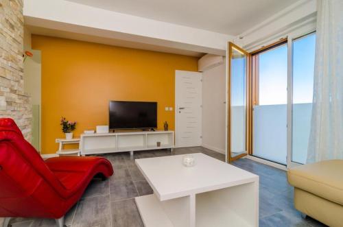 - un salon avec une chaise rouge et une télévision dans l'établissement Apartment Lula, à Orašac