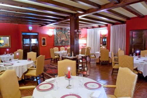 un restaurante con mesas y sillas blancas y paredes rojas en Hotel Villa Montanarini, en Villarotta