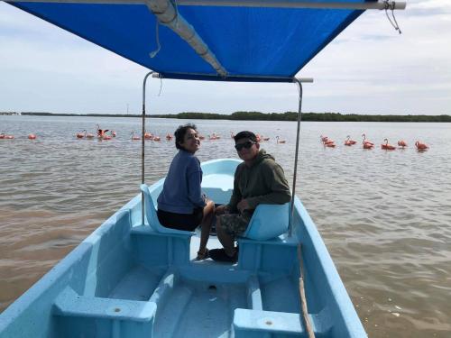dos personas sentadas en un bote azul en el agua en Hotel Posada Mercy, en Río Lagartos