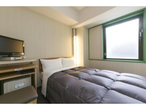 a hotel room with a bed and a television at R&B Hotel Shin Yokohama Ekimae - Vacation STAY 14695v in Yokohama