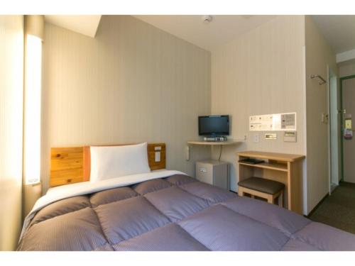 Schlafzimmer mit einem Bett, einem Schreibtisch und einem TV in der Unterkunft R&B Hotel Kumagaya Ekimae - Vacation STAY 14848v in Kumagaya