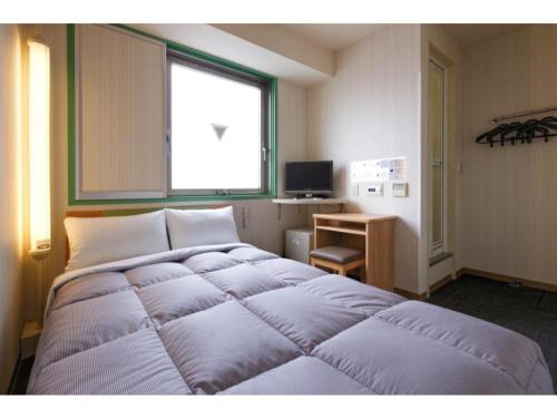福岡的住宿－R&B Hotel Hakata Ekimae 1 - Vacation STAY 16386v，一张位于带窗户和书桌的客房内的床铺