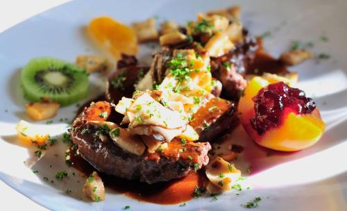 a white plate of food with fruit and meat at Hirschen-Dorfmühle in Biederbach Baden-Württemberg