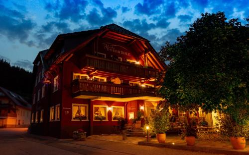a red building with a balcony on a street at Hirschen-Dorfmühle in Biederbach Baden-Württemberg