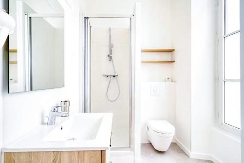 een witte badkamer met een wastafel en een toilet bij La Reine Blanche in Dammarie-lès-Lys