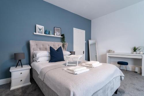 a bedroom with a large bed with blue walls at South View - 3 bed modern Chester house - Close to city centre in Chester