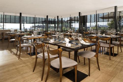 a restaurant with tables and chairs and windows at Pullman Vina del Mar San Martin in Viña del Mar