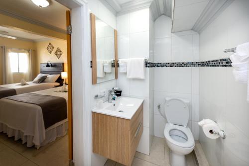 a bathroom with a toilet and a sink and a bed at Baker's Suites in Simpson Bay