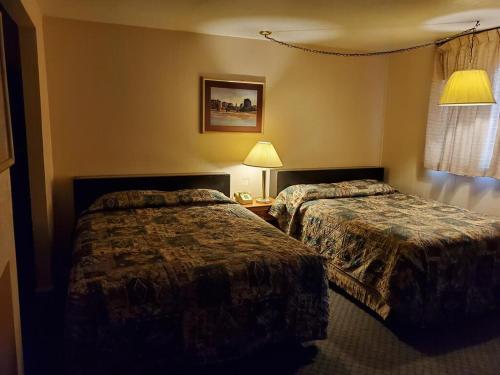 a hotel room with two beds and two lamps at Sands Motel in Grants