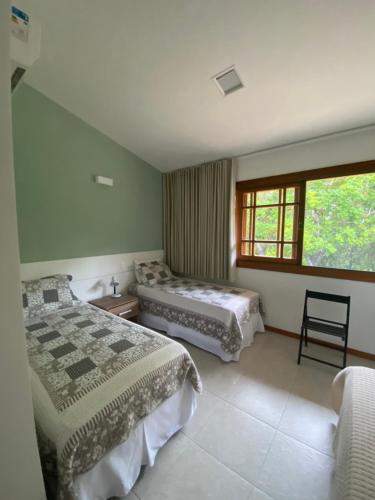 ein Schlafzimmer mit zwei Betten und einem Fenster in der Unterkunft Apartamento 2 suítes em condomínio de luxo no centro in Praia do Forte