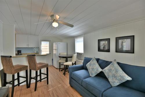 a living room with a blue couch and a kitchen at Charming Beach Cottage Steps to Siesta Beach and Village Shops and Restaurants in Sarasota