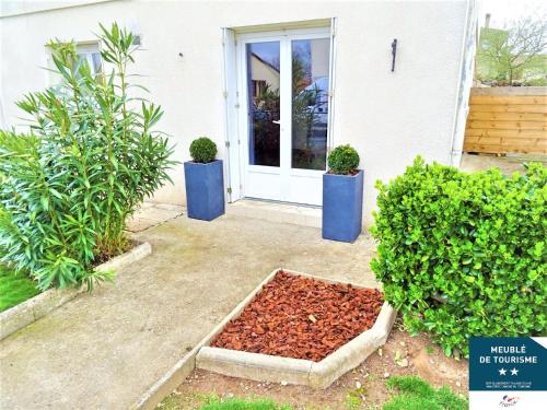 uma casa com dois vasos de plantas na frente de uma porta em Locations Avec Jardins Privatifs em Bergerac