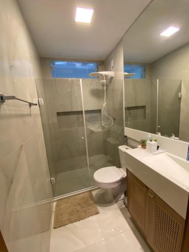 ein Badezimmer mit Dusche, Toilette und Waschbecken in der Unterkunft Apartamento 2 suítes em condomínio de luxo no centro in Praia do Forte