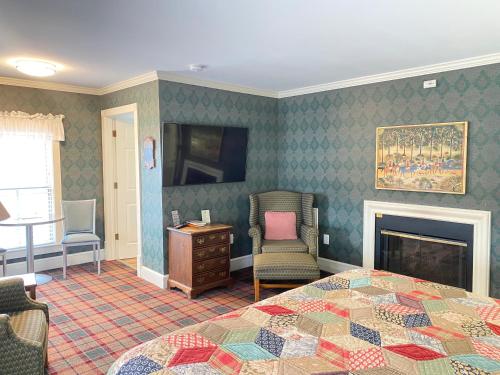 a bedroom with a bed and a chair and a fireplace at Harbor House Inn in Grand Haven