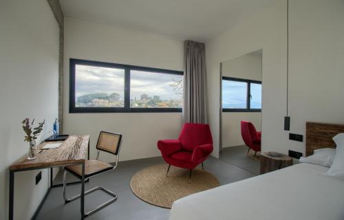a bedroom with a bed and two chairs and a desk at AFTER Hotel in Bastiagueiro
