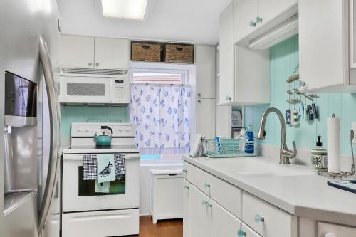 a kitchen with white cabinets and a white refrigerator at Sol Mate Beach Cottage in St Pete Beach