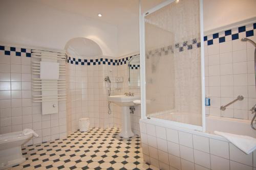 a bathroom with a toilet, sink and bathtub at Parkhotel Unter den Linden in Halberstadt