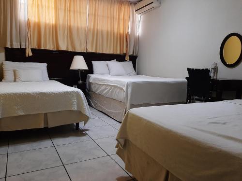 a hotel room with two beds and a mirror at Hotel San Jose Hostal in San Salvador