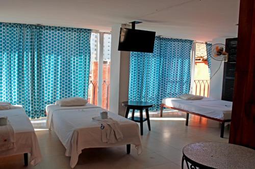 a room with two beds with blue curtains and a tv at Hotel Condesa Americana Acapulco in Acapulco