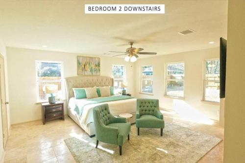 a bedroom with a bed and two green chairs at Vacation Pool House in the Serene Wilderness - Robert E Lee in Conroe