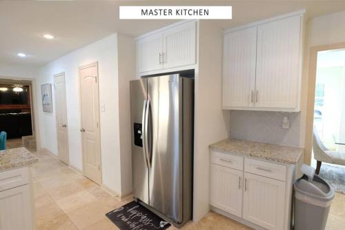 a kitchen with a stainless steel refrigerator and white cabinets at Vacation Pool House in the Serene Wilderness - Robert E Lee in Conroe