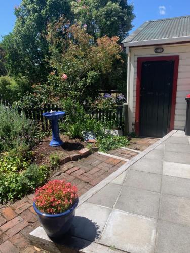 a garden with a blue birdbath and flowers in front of a house at Villa in the Vines in Martinborough 
