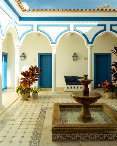 a courtyard with a fountain in a building with blue doors at Hotel Solar do Arco in Cabo Frio