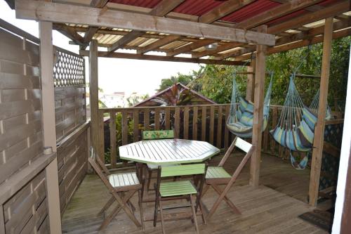 um alpendre com uma mesa, cadeiras e redes de descanso em an eol caraibes em Trois-Rivières