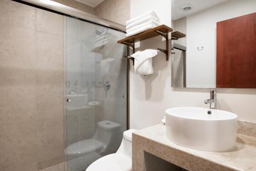 y baño con lavabo, ducha y aseo. en Hotel Ave Inn, en Mazatlán