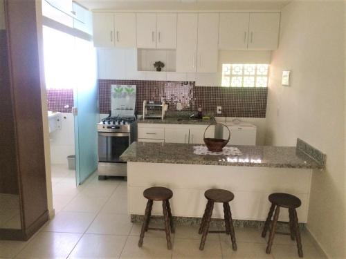 a kitchen with a counter and two stools at Pedra do Imperador - Apartamento in Nova Friburgo