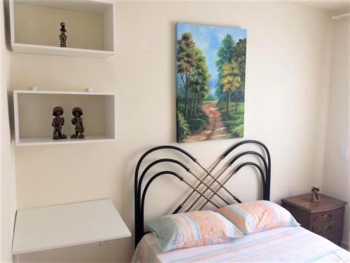 a bedroom with a bed and a painting on the wall at Pedra do Imperador - Apartamento in Nova Friburgo