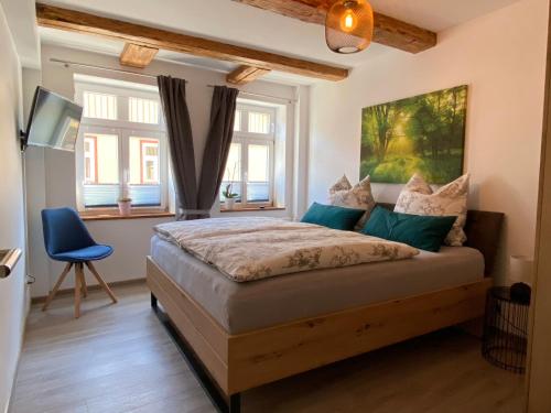 a bedroom with a bed with a blue chair and windows at Mountain apart Ferienwohnungen im Harz in Wernigerode