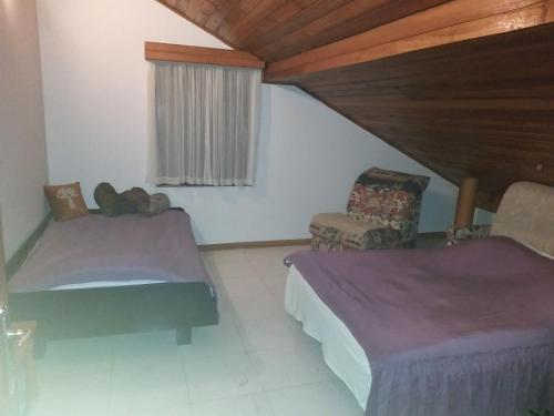 Cette chambre dispose de deux lits, d'une chaise et d'une fenêtre. dans l'établissement vila zelenac, à Požega