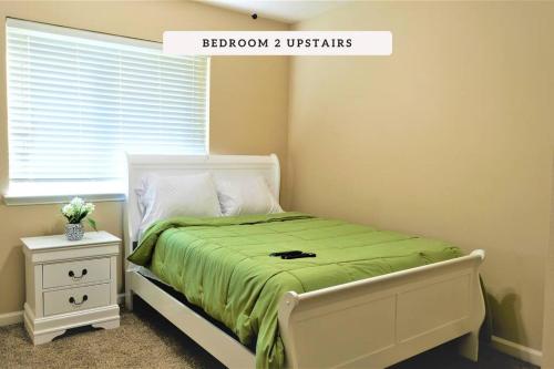 1 dormitorio con 1 cama con manta verde y ventana en Exceptional, 5 Beds, Near Downtown - Bold Ruler en Stafford