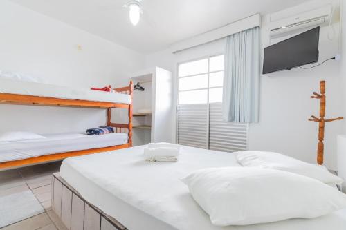 ein weißes Zimmer mit zwei Betten und einem Fernseher in der Unterkunft Pousada Santa Ana in Florianópolis