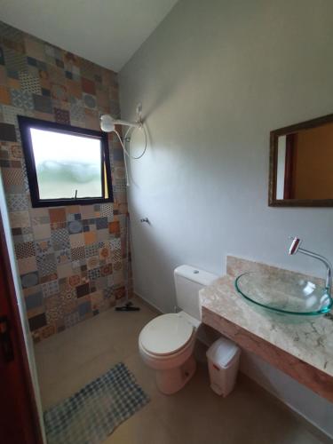a bathroom with a toilet and a sink and a window at Espaço Casa na Rocha in São José dos Campos