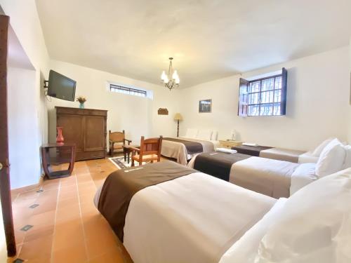 uma sala de estar com várias camas e uma televisão em Casa del Carmen - Villa de Leyva em Villa de Leyva