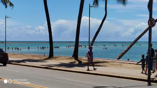 a beach with palm trees and people in the water at Studio Time 1312 - Luxo - Ponta Verde - Maceió-AL in Maceió