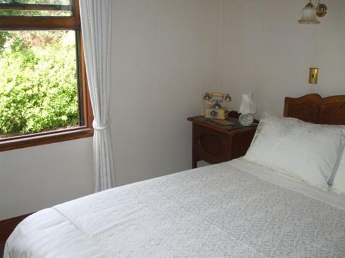 a bedroom with a white bed and a window at Villa in the Vines in Martinborough 