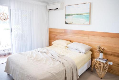 Schlafzimmer mit einem weißen Bett mit einem Kopfteil aus Holz in der Unterkunft Byron Bay Accom Unit 3 34 Kendall Street - Three by the Sea in Byron Bay