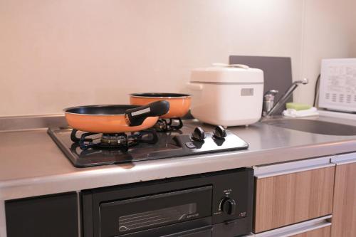 a kitchen with two pots on a stove top at 谷町君 星ホテル 新深江59 in Osaka