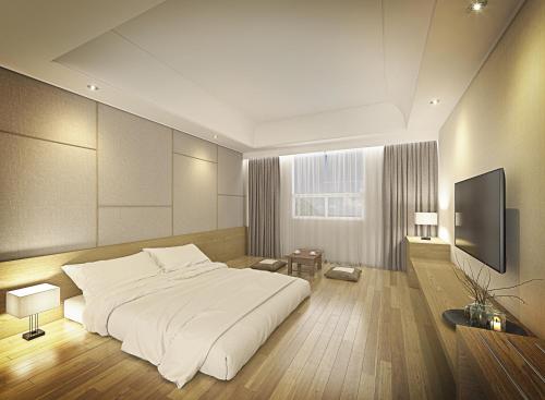 a bedroom with a large bed and a flat screen tv at Crown Hotel Changwon in Changwon