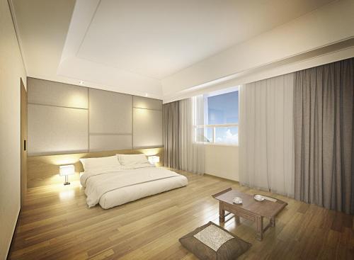 a bedroom with a bed and a table and a window at Crown Hotel Changwon in Changwon