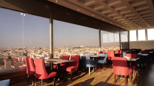 a restaurant with red chairs and tables and a view at Eva Hotel in Jeddah
