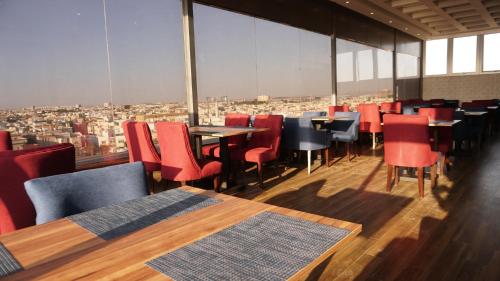 a restaurant with tables and chairs and a view of a city at Eva Hotel in Jeddah