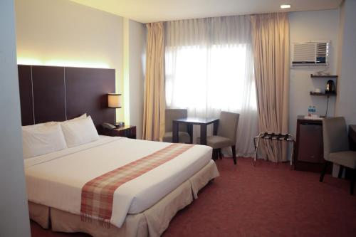 a hotel room with a bed and a desk and a window at Casablanca Suites Near Airport in Legazpi