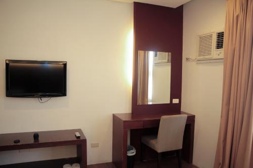 a room with a tv and a chair and a mirror at Casablanca Suites Near Airport in Legazpi